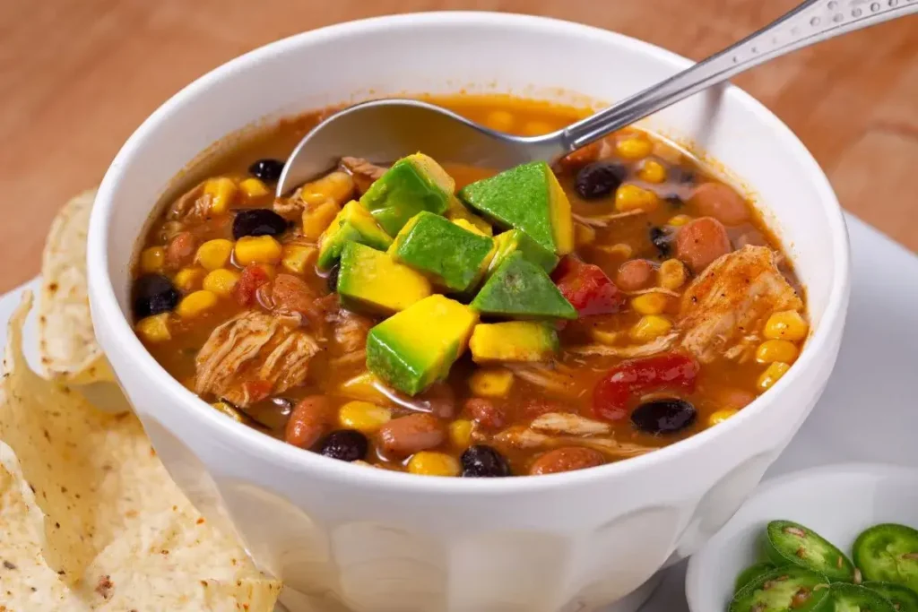 Warm bowl of chicken taco soup on a rustic table, symbolizing the popularity of this comforting dish.