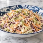 Bowl of creamy coleslaw topped with fresh dill and a sprinkle of black pepper