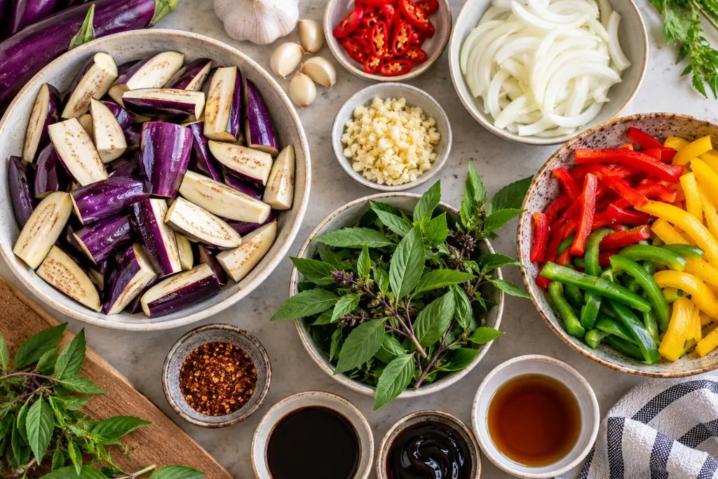 Sliced Thai eggplant, garlic, chili, onion and red, green and yellow bell peppers prepared for a Thai stir-fry